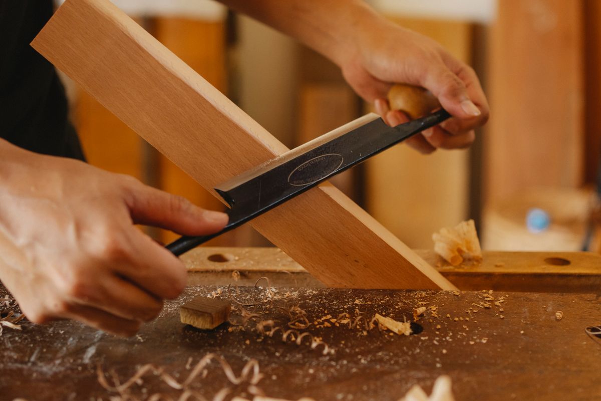 Artisan shaping wood with hand tools in a workshop