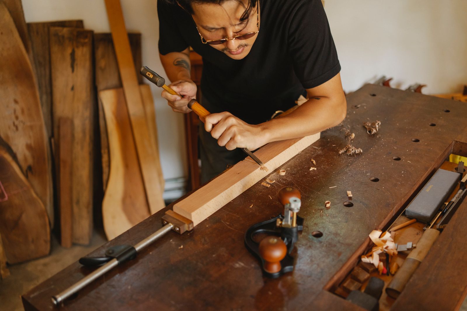 Craftsman shaping wood at a workshop bench