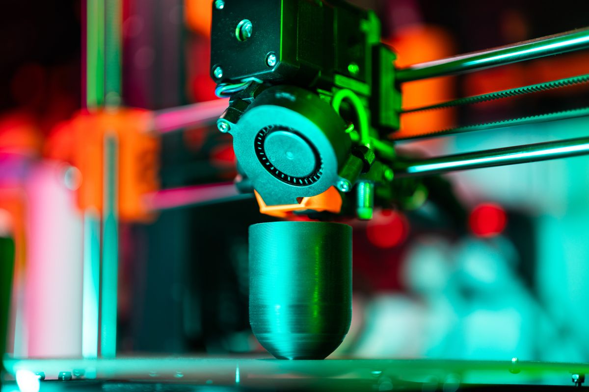 3D printer creating a part under neon lighting